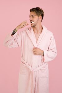 man brushing his teeth in bathrobe