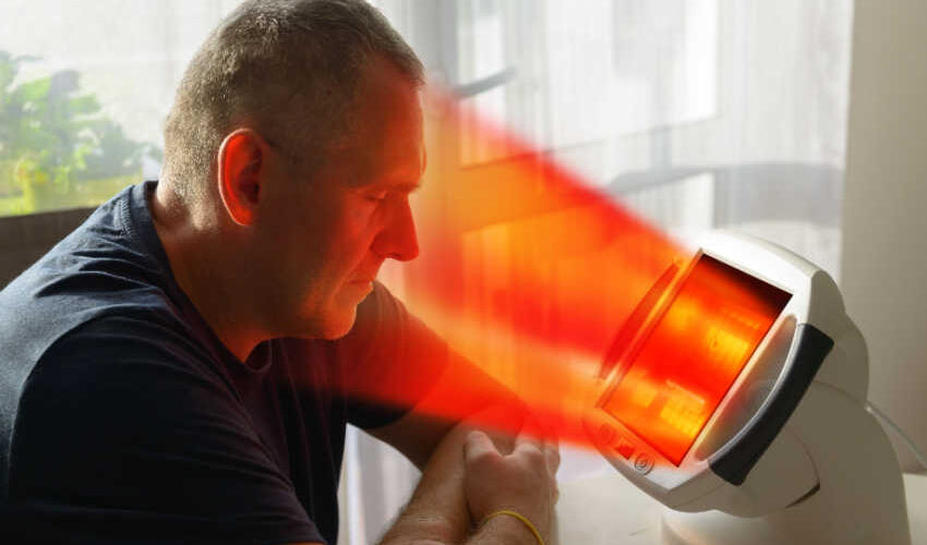 Man reaping benefits of photobiomodulation by using a red light therapy lamp to improve blocked sinuses